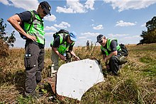 Un groupe de personnes dans un champ, autour d'un débris d'avion.