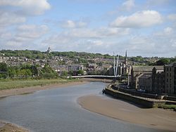 Řeka Lune ve městě Lancaster, přes kterou vede Millenium bridge. Městu dominuje štíhlá věž lancasterské katedrály, na obzoru výrazný Ashtonův památník.