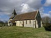 A mainly flint church with red tied roofs and a bellcote with a spirelet