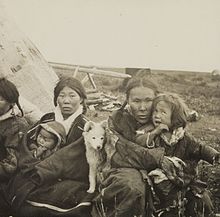 Photographie de deux femmes et de leurs deux enfants indigènes (Kètes) avec un chiot blanc devant leur tente.