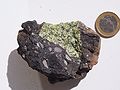 Xenolith mantel peridotit (hijau) di dalam suatu bom volkano (gelap) dari Vulkan-Eifel, Jerman. Syiling satu euro untuk skala.