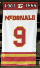 A white, rectangular banner with red and yellow trim at the top and bottom. It reads "1981 – 1989 McDONALD 9"