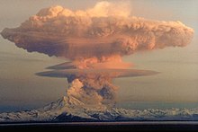 A large ash cloud rising into the air from an erupting volcano