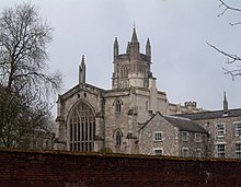 Medieval stone church with a large arched window at one end and a square tower