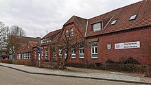 Schulgebäude der Oberschule Obenstrohe; roter Klinkerbau mit Bushaltestelle davor