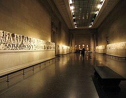 Longue salle lambrissée, frises de chaque côté à hauteur d'homme.