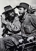 Camilo Cienfuegos (left) watching Fidel Castro (right) speak after the victory of the Cuban Revolution