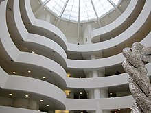 Photographie prise en contre-plongée à l'intérieur du musée Guggenheim montrant la rampe et la verrièreux.