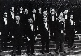 photo de groupe des ministres. Une douzaine d'hommes debout en costumes sont rassemblés en bas d'un large escalier.