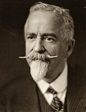 A black-and-white photograph of a man in a suit with a tie