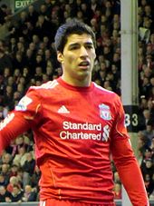 The head and torso of a man with short, dark hair. He is wearing a red shirt.