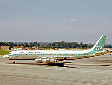 DC-8 stationné, vu de profil, livrée blanche et verte.