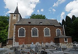 Religious building in brick in Neo-Romanesque style. In the foreground, a cemetery, in the background, a forest.