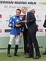 Der Präsident des Kölner Rennvereins Eckard Sauren gratuliert dem siegreichen Jockey Jason Watson