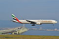 Un Boeing 777 de la compagnie Emirates, atterrissant à Kansai. En toile de fond, le pont reliant l'aéroport à la Préfecture d'Osaka sur l'île principale du Japon, Honshu.