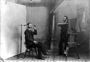 In this 1893 multiple-exposure trick photo, the photographer appears to be photographing himself. It satirizes studio equipment and procedures that were nearly obsolete by then. Note the clamp to hold the sitter's head still.