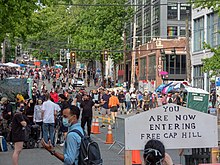 Crowded street, with barricades and a sign