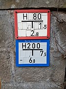 Red fire hydrant marker plate in Germany, along with another blue special-purpose water hydrant marker plate – The numbers indicate the diameter (80 mm) and the location (2.8 meter in the back, 1.5 meter to the right).