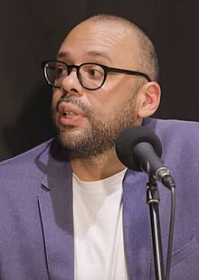 Headshot of al-Gharbi facing left, in a purple suit