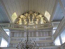 Interior of a church, facing the rear with the organ on the third tier. The front of the organ is decorated with small Baroque golden ornaments.