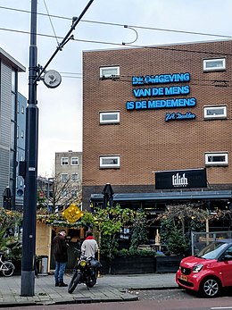 Blik op Nieuwe Binnenweg 125, met quote op het gebouw: "De omgeving van de mens is de medemens" (Jules Deelder).