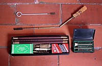 An assortment of cleaning rods: A short cleaning rod with a brass brush attached, a foldable cleaning rod with a nylon brush attached, a cleaning kit for a shotgun (note the thicker rod), and some different brushes.