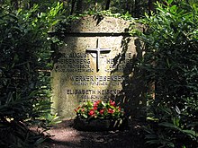 A gravestone surrounded by vegetation. On it are the four names and dates, with August and Annie at the top on either side of a large cross. Below the cross Werner and Elisabeth are listed.