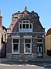 Woonhuis met fraai gedecoreerde voorgevel in vrije ambachtelijke stijl. Woning op rechthoekige plattegrond, dwarskap. Pand introduceert verspringing in straatwand.