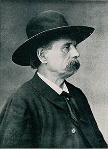 Portrait photographique d'un homme pris de profil, portant un chapeau rond et une moustache épaisse.