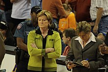 Pat Summitt, les bras croisés. Une assistance à ses côtés écrit sur une tablette.