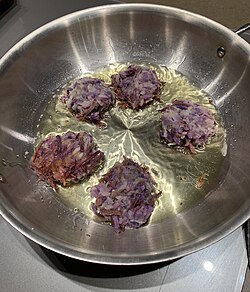 Purplish latkes frying in oil in a pan