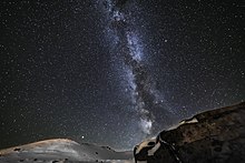 Dans une nuit saupoudrée d'étoiles, un voile blanc forme deux lignes proches d'amas parallèles.