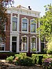 Groot woonhuis in eclectische stijl op rechthoekige plattegrond. Twee woonlagen en zolder. Asymmetrisch opgezette lijstgevel met drie vensterassen. Rijk geornamenteerd hoofdgestel. Smalle entreebeuk verbijzonderd tussen twee stucpilasters.