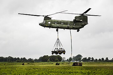 A Dutch CH-47D hauls slung light vehicles and another load on exercises, 2015.