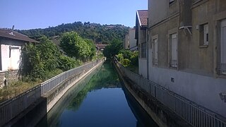 Rivière encadrée de bâtiments et de verdures.