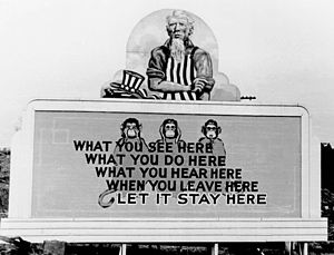 Uncle Sam has removed his hat and is rolling up his sleeves. On the wall in front of him are three monkeys and the slogan: What you see here / What you do here / What you hear here / When you leave here / Let it stay here.