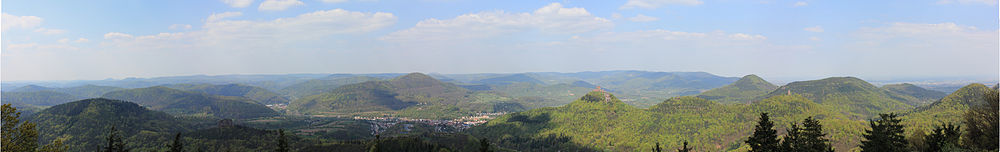 Het Paltserwoud is een zwaar ingesneden laaggebergte met veel heuvelvormen en dichte bebossing: panoramisch uitzicht vanaf de Rehberg(toren) op de Trifels in noordelijke richting