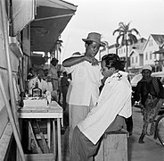 Un coiffeur en plein air et un client, dans une rue de Paramaribo dans l'ancienne Guyane néerlandaise, en 1955.