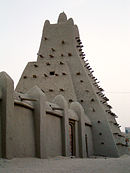 A mud building with wooden spikes sticking out of it