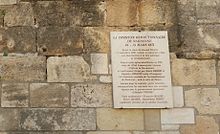 Texte gravé sur une plaque en marbre fixée sur un mur.