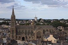 Photographie de la façade sud de l'église prise depuis un point élevé de la chapelle du Kreisker. On voit les flèches à gauche, puis la nef avec le porche, le transept sud et le chevet.