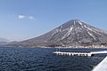 Vue d'un volcan au bord d'un lac sous un ciel bleu nuageux.