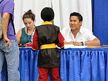 Man and woman seated at table conversing with adult and youth.