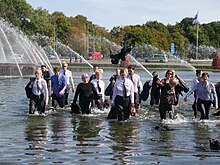 Mehrere Künstler und Künstlerinnen waten durch das Wasser