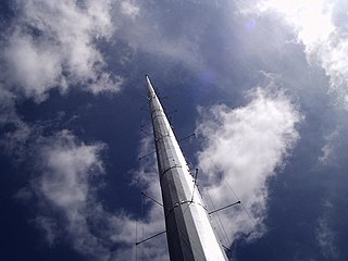 Folded unipole antenna with a solid metal mast surrounded by six skirt wires, held away by insulated standoffs