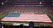 A large flag displayed during the singing of The Star-Spangled Banner prior to the start of an NFL game.