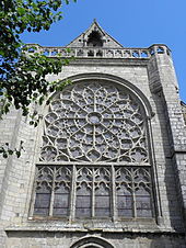 Photographie d'un pignon de transept d'église, avec une rose à remplage rayonnant.