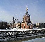 A church with a red facade and other buildings in snow