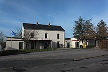 La façade du bâtiment de la mairie, avec, à sa droite, l'annexe postale, vus de l'extrémité du parking