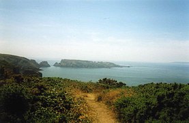 Vue de Brecqhou depuis la grande Sercq, au nord, on aperçoit la côte de Guernesey à l'horizon.